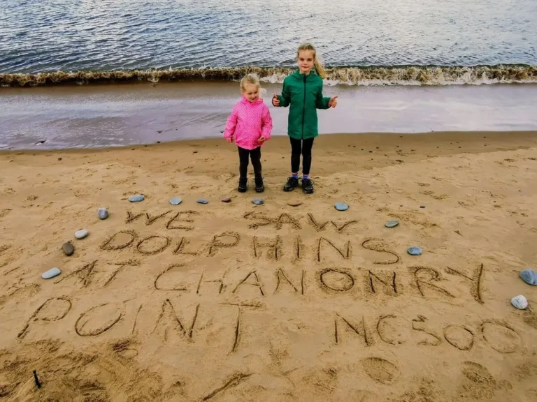 Our two girls on the beach near Rosemarkie Campsite. Written in the sand is "We saw Dolphins at Chanonry Point"