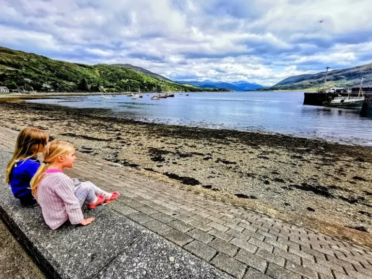 The girls sitting down looking across the loch from Ullapool.