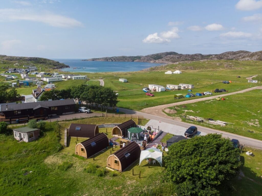 Aerial shot of glamping pods near Achmelvich Beach on the North Coast 500, with turquoise waters and rugged coastline in view