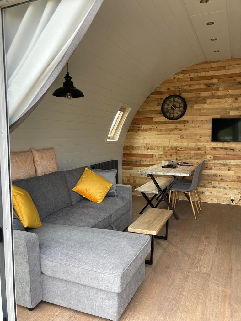 Comfortable sofa inside a Brora glamping pod on the North Coast 500, with natural wood walls and soft furnishings