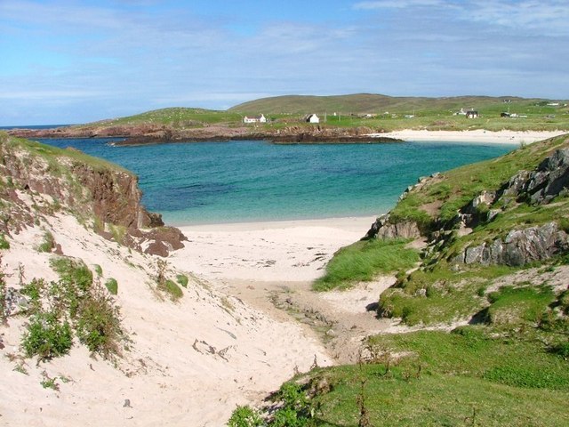 Small sandy inlet at Clachtoll Bay, with red Torridonian Sandstone on the left and grey Lewisian Gneiss rocks on the right.