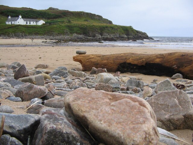 Sandy Farr Bay Beach in Bettyhill, Scotland, with gentle surf and grassy dunes in the background.