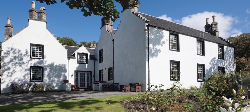 Exterior view of Scourie Lodge and Gardens, a charming bed and breakfast along the North Coast 500 route, surrounded by lush greenery.