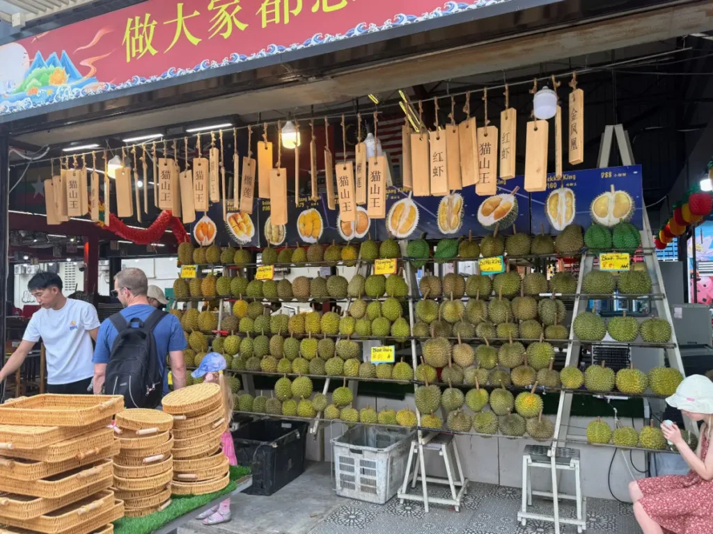 Durian stall in Kuala Lumpur with labeled varieties and colorful signage—an authentic local experience during our Malaysia itinerary.