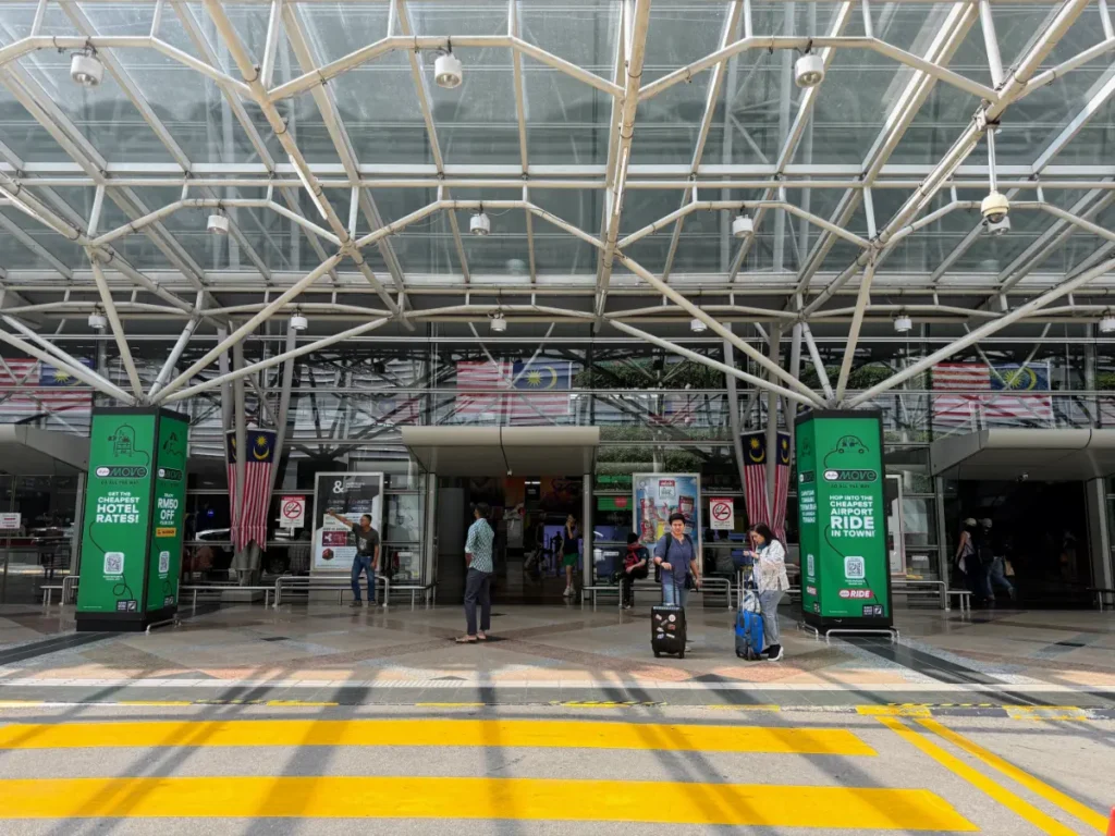 Entrance to KL Sentral Station in Kuala Lumpur, with GRAB signage and travellers—central hub for getting around Malaysia.