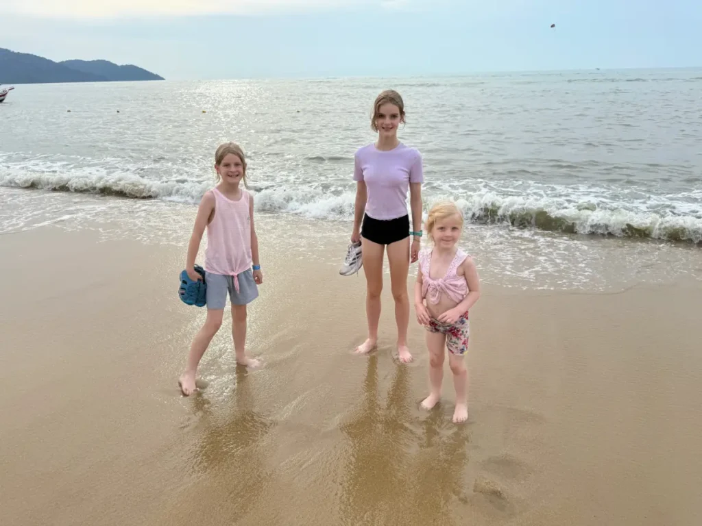 Children standing barefoot on Batu Ferringhi Beach in Penang