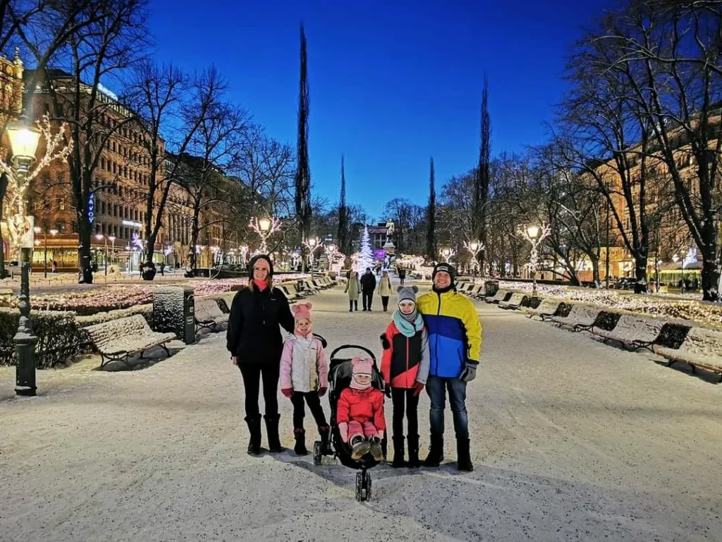 Our family posing in a snowy, illuminated park in Helsinki, Finland during a winter evening.