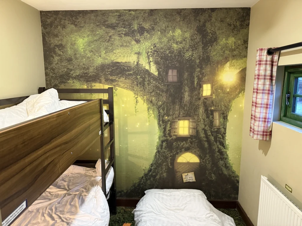 Bunk-bed room with glowing enchanted tree mural at Alton Towers Enchanted Village during Santa Sleepover