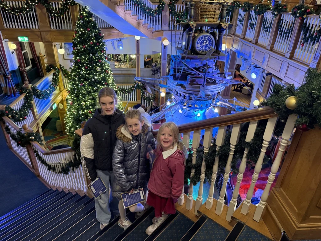 Children on staircase inside Clocktree with Christmas tree and steampunk clock at Alton Towers Santa Sleepover