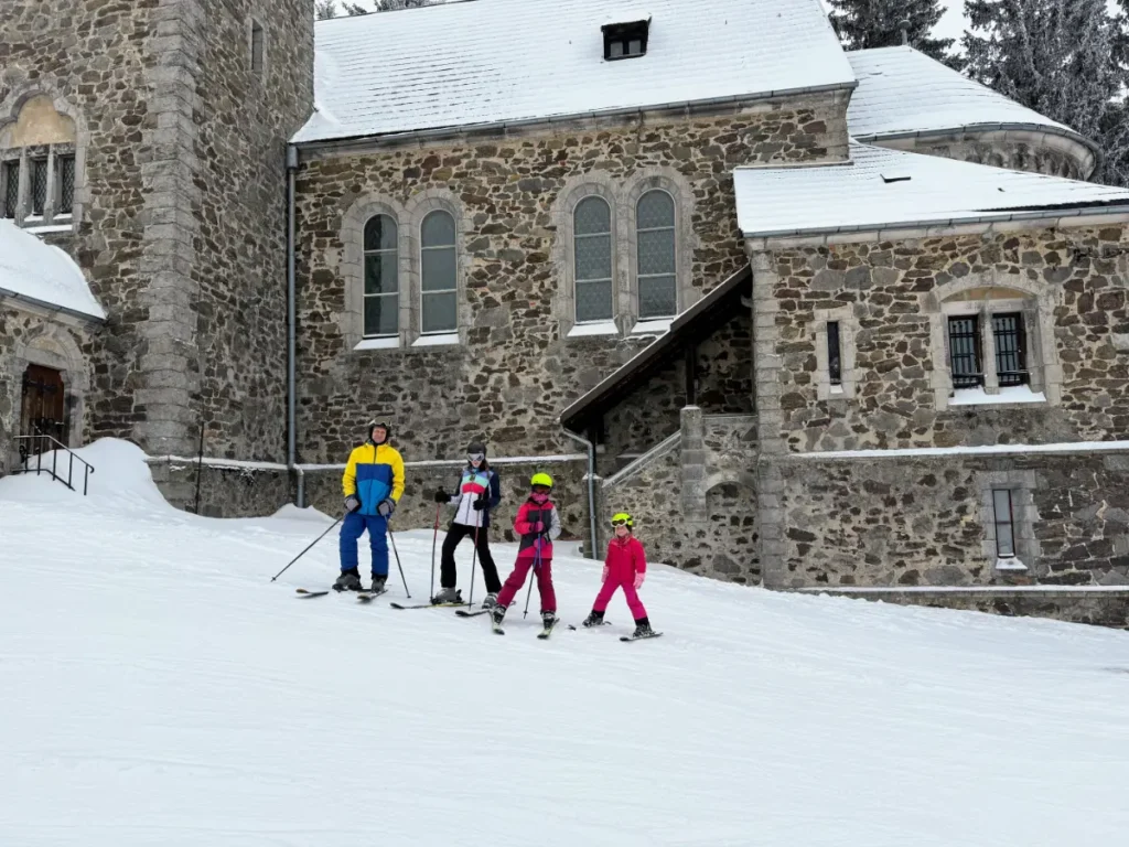 Family standing in front of the church in Zieleniec Ski Arena, a beginner ski resort in Poland