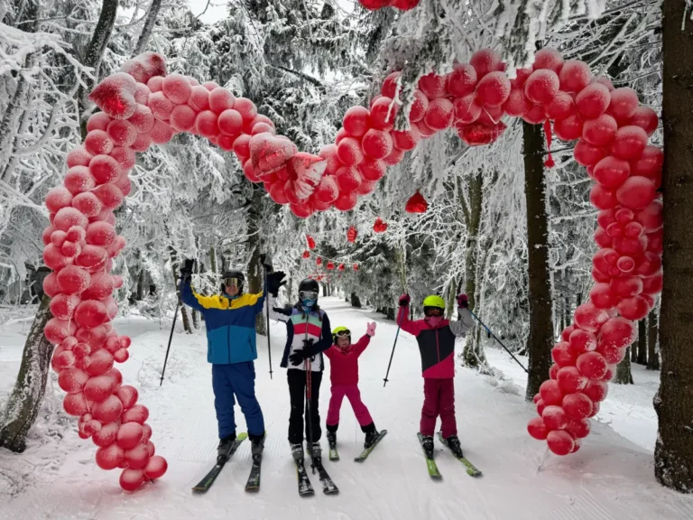 Family skiing through a snowy forest trail at Zieleniec Ski Arena, a beginner ski resort in Poland with scenic runs